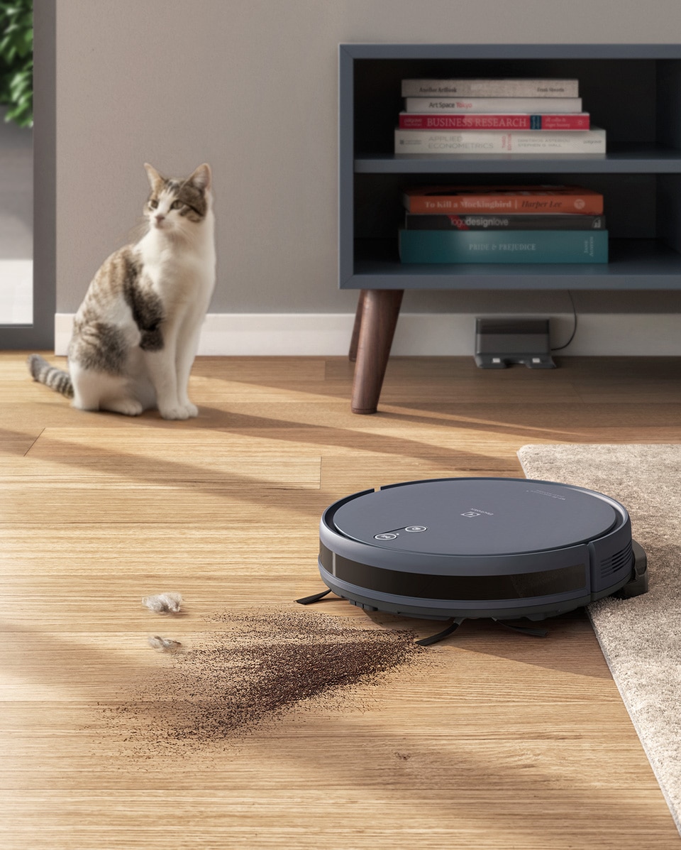 Robô aspirador limpando o piso com um gato ao fundo